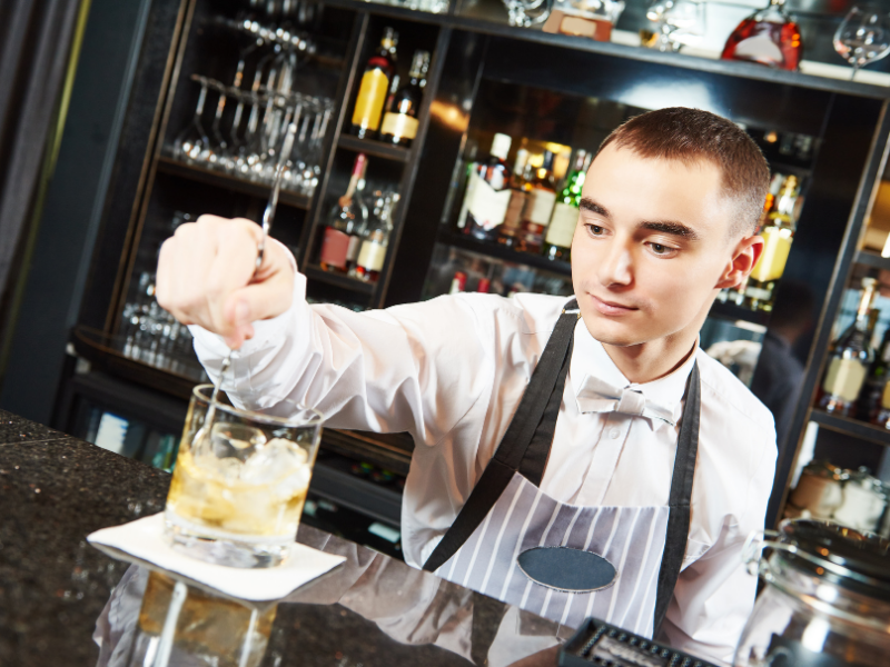 A bar tender prepares a drink