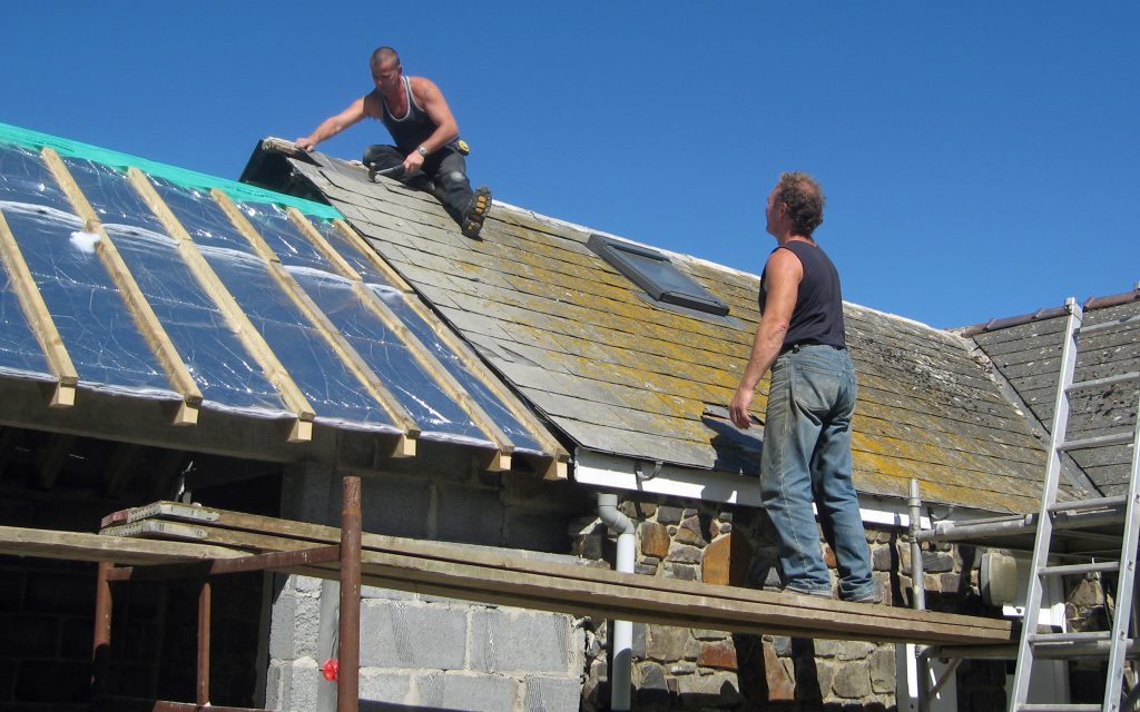 Two men fixing a roof
