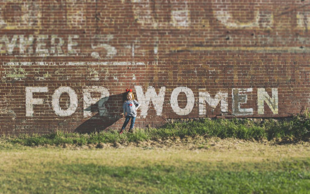 A child next to a wall saying for women