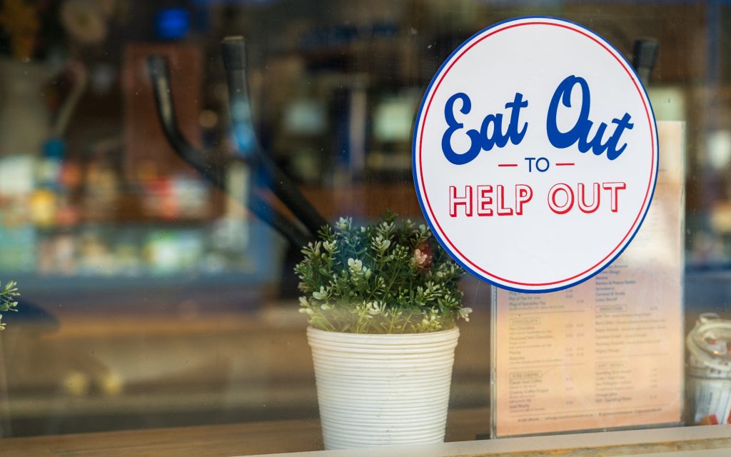 A sign in a window saying eat out to help out