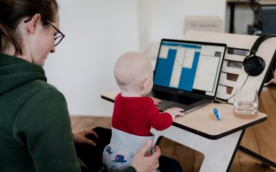 A woman holding a baby by a computer