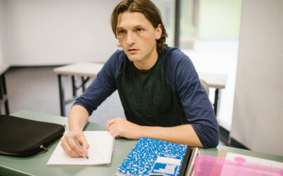Male learner in blue sweater sitting an exam looking puzzled
