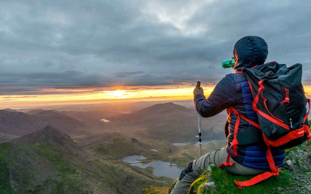 Hiker on top of Yr Wyddfa looking out at sunset