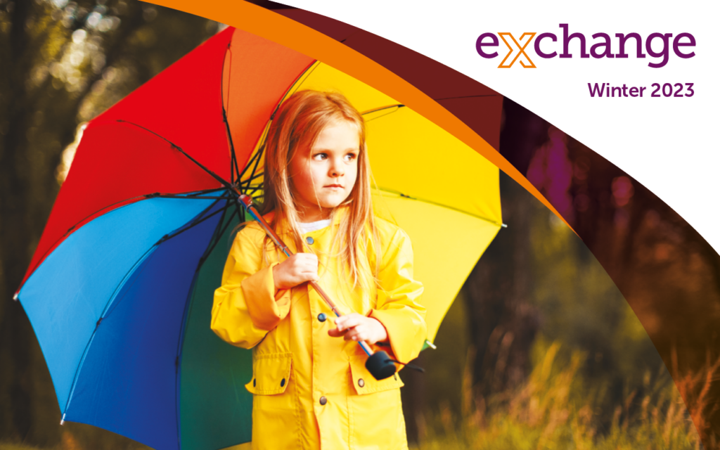 Young girl wearing a yellow raincoat and holding a multi-coloured umbrella