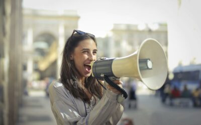 Cheerful young woman shouting into a megaphone